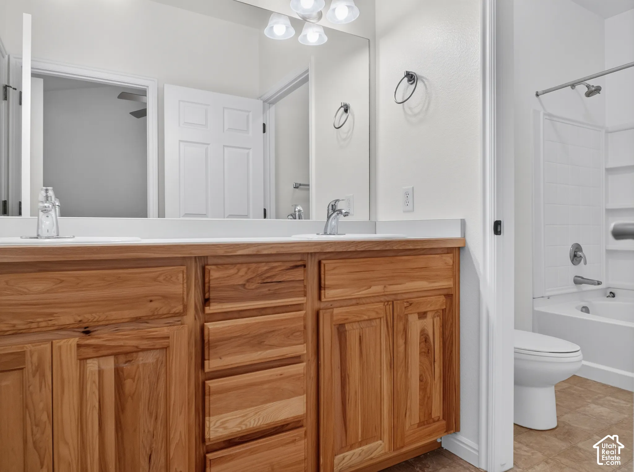 Dual vanity with wood-finish cabinetry and chrome fixtures, featuring an integrated mirror and overhead lighting