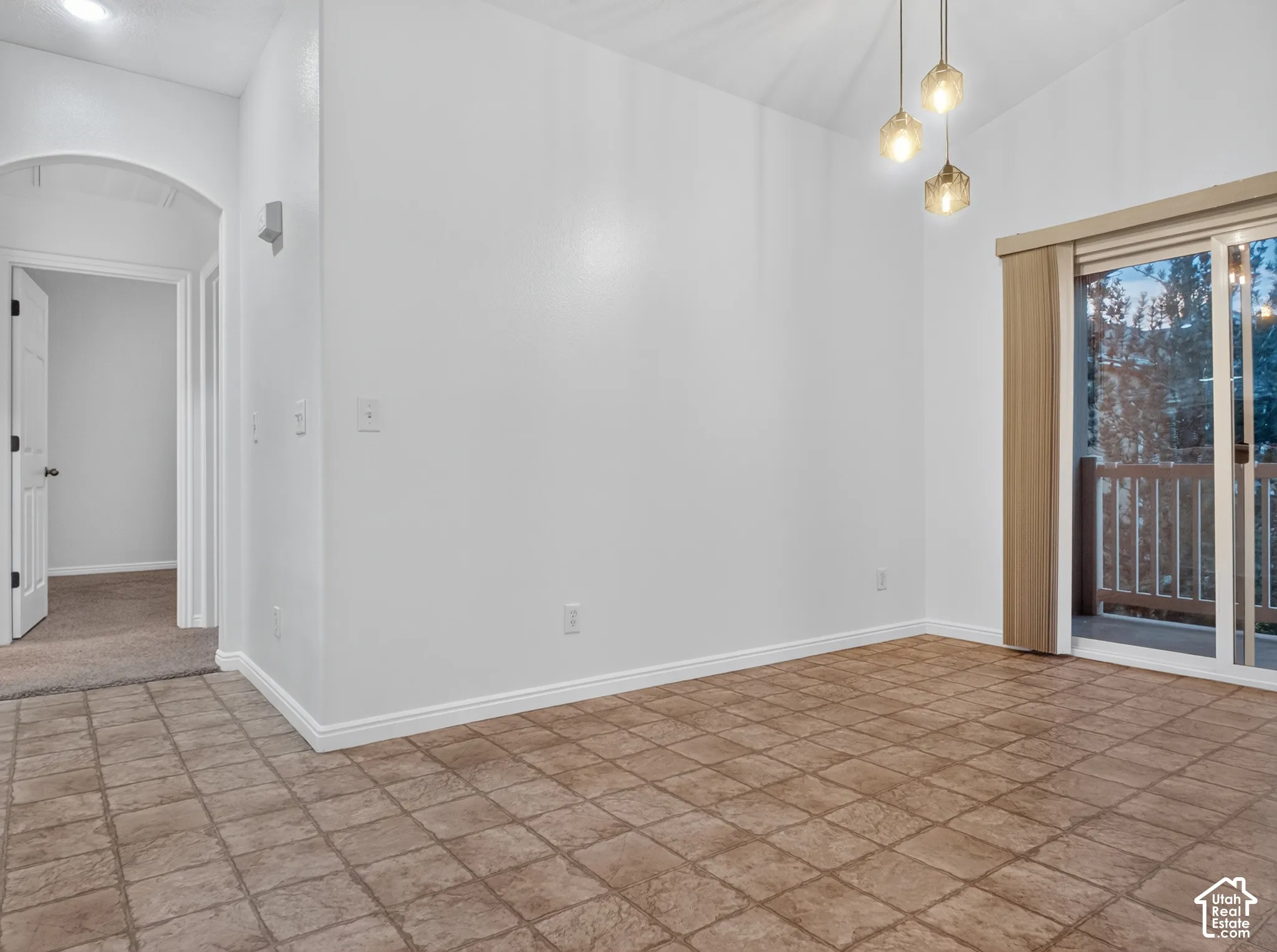 Arched hallway entry, tile flooring, contemporary pendant lighting, and a sliding glass door to an exterior balcony