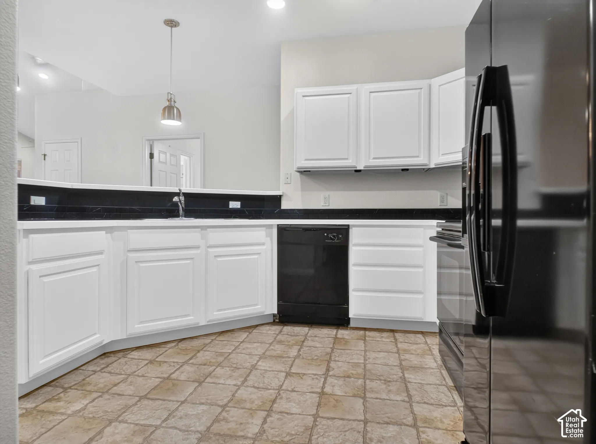 White cabinetry with dark countertops, a built-in sink, and a black dishwasher