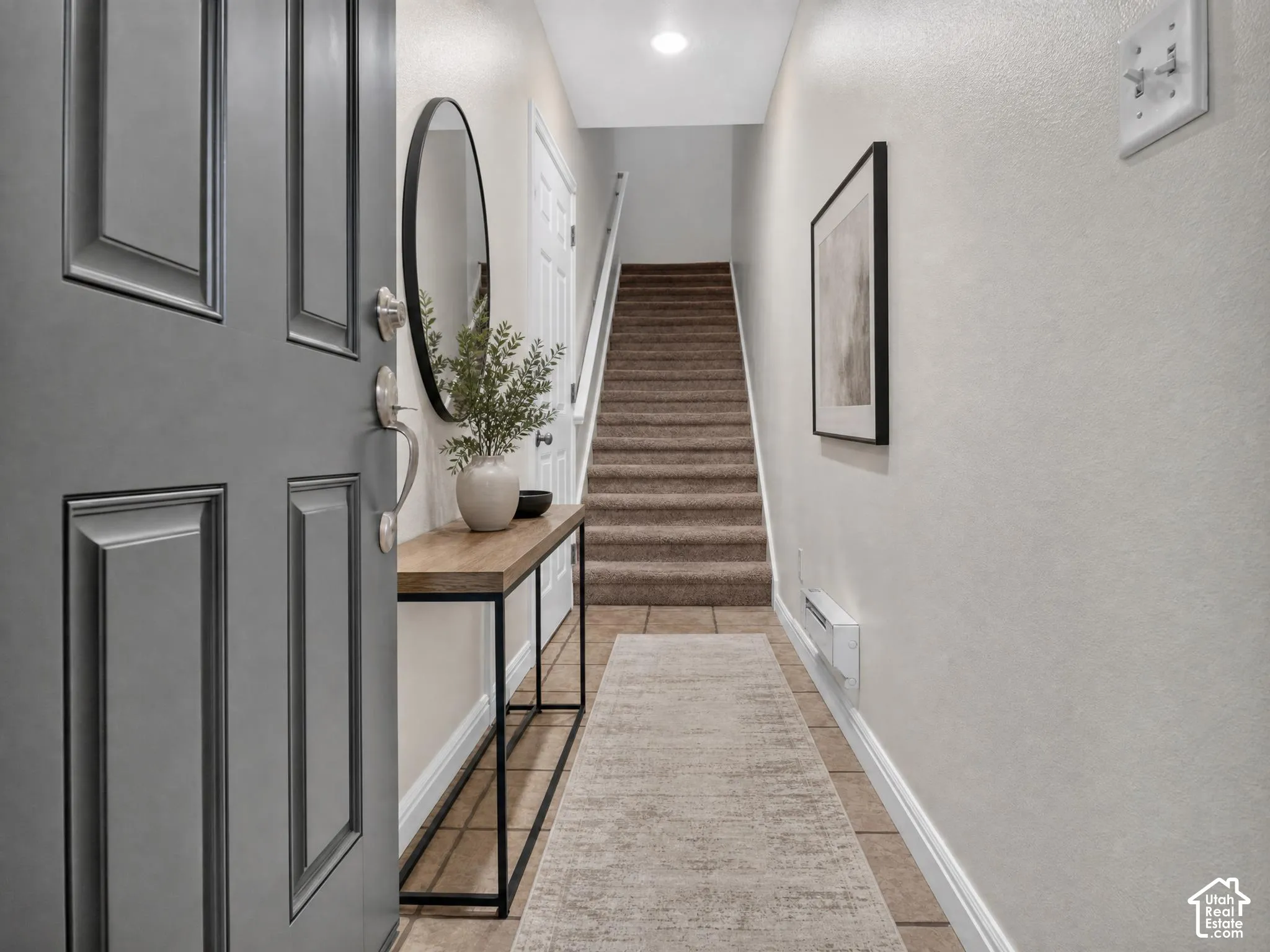 Entryway featuring a paneled door with brushed nickel hardware, tiled flooring, and a carpeted staircase