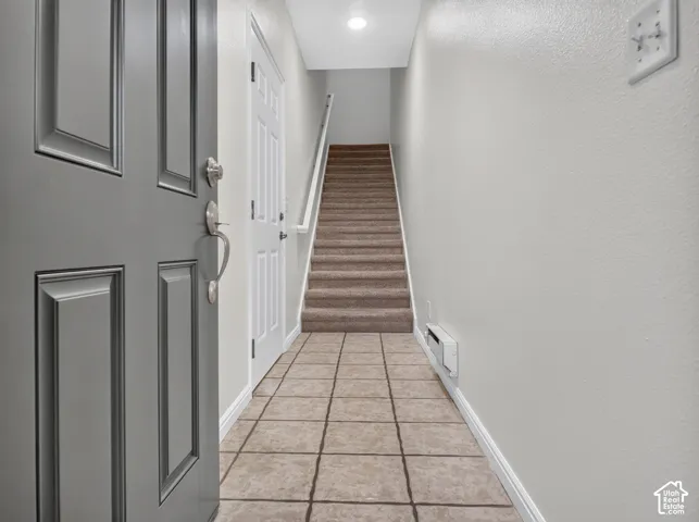 Tiled entry foyer with a paneled main door and neutral wall finishes