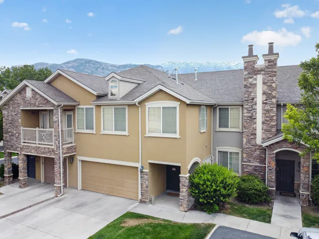 Multi-level residence featuring a stone and stucco exterior, prominent two-car garage, and a second-story balcony