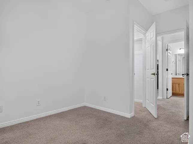 Neutral carpet flooring, white walls, white trim, and a white six-panel interior door