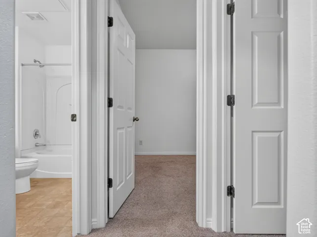 Full bath with a white shower/tub combination, toilet, and wood-finish flooring