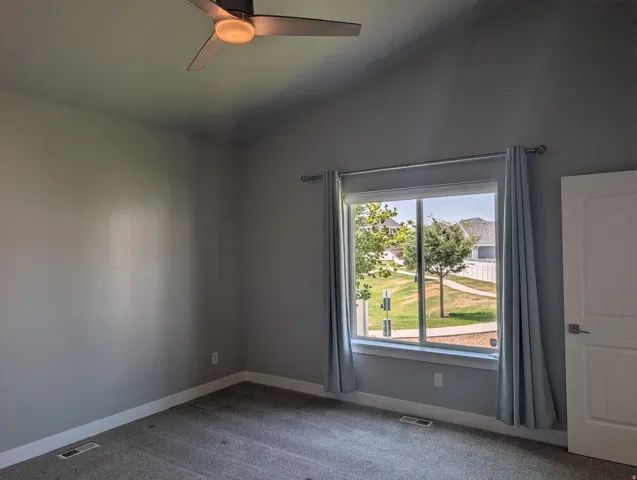 Carpeted room featuring a vaulted ceiling and a ceiling fan