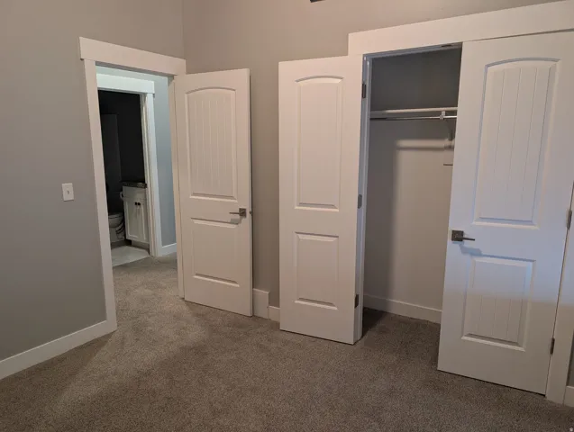 Neutral-toned carpeted flooring with white baseboards and trim