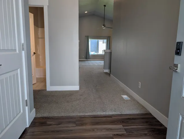 Entryway featuring wood-finish flooring transitioning to carpet, with a digital keypad entry system