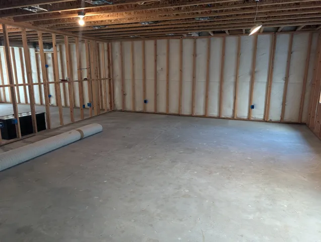 Unfinished basement featuring extensive wood framing, insulated walls, concrete flooring, and exposed ceiling joists