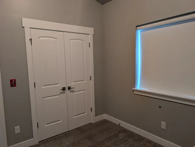 Neutral tone wall paint with white trim, featuring a double-door closet with dark hardware