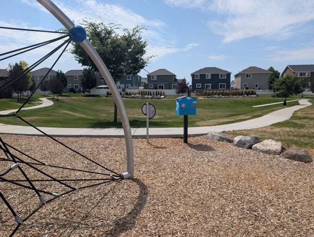 Park grounds featuring wood chip surfacing, climbing apparatus, and decorative rock elements