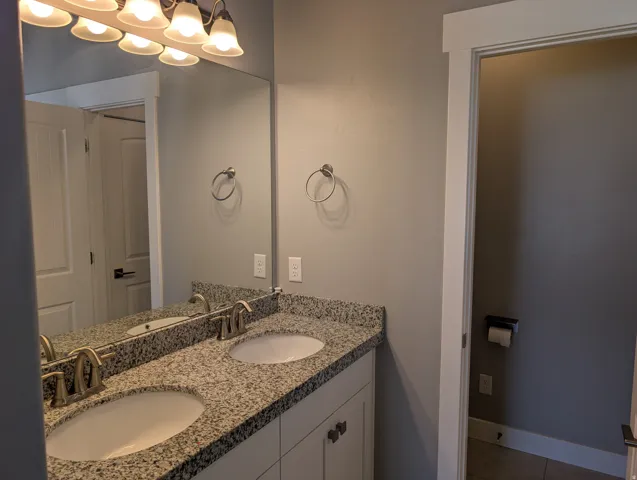 Double vanity featuring undermount sinks and a speckled countertop