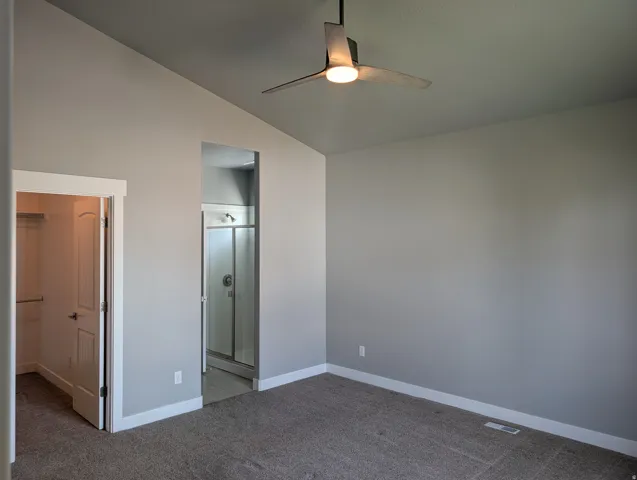 Carpeted room featuring a vaulted ceiling and a ceiling fan with integrated lighting
