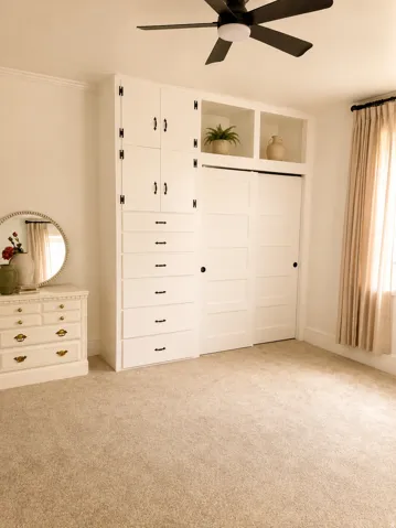 Built-in cabinetry with black hardware, integrated shelving, and sliding closet doors