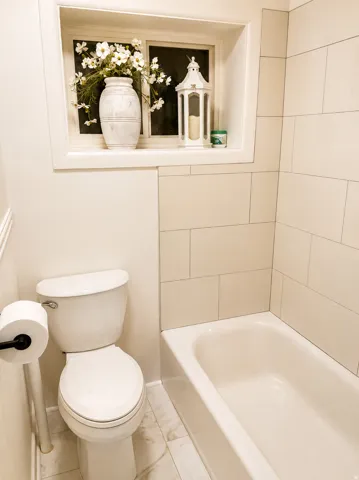 Tiled bath surround, built-in window niche, and porcelain tile flooring