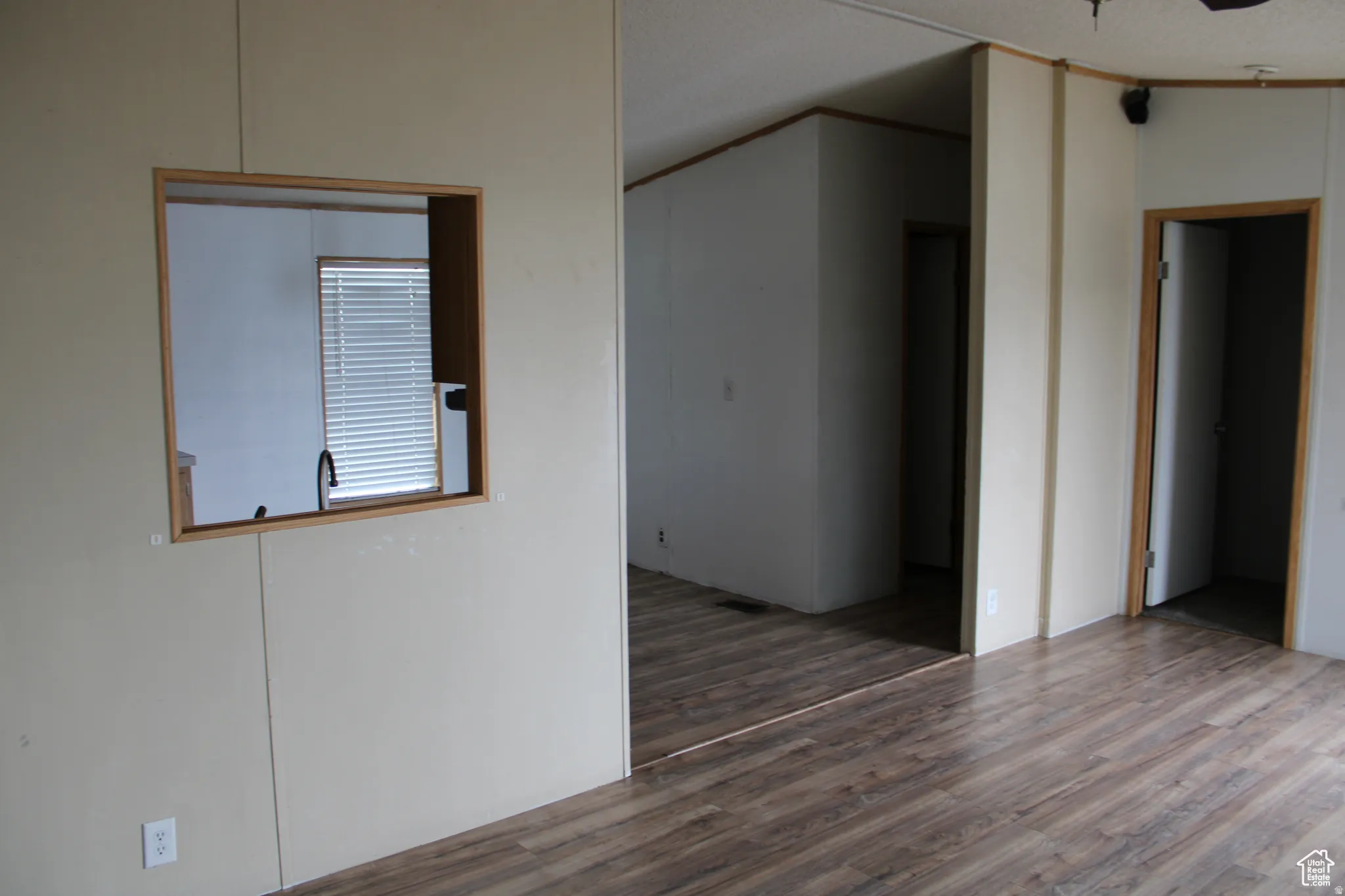 Interior space featuring wood-finish flooring, a pass-through window with wood trim, and multiple doorways