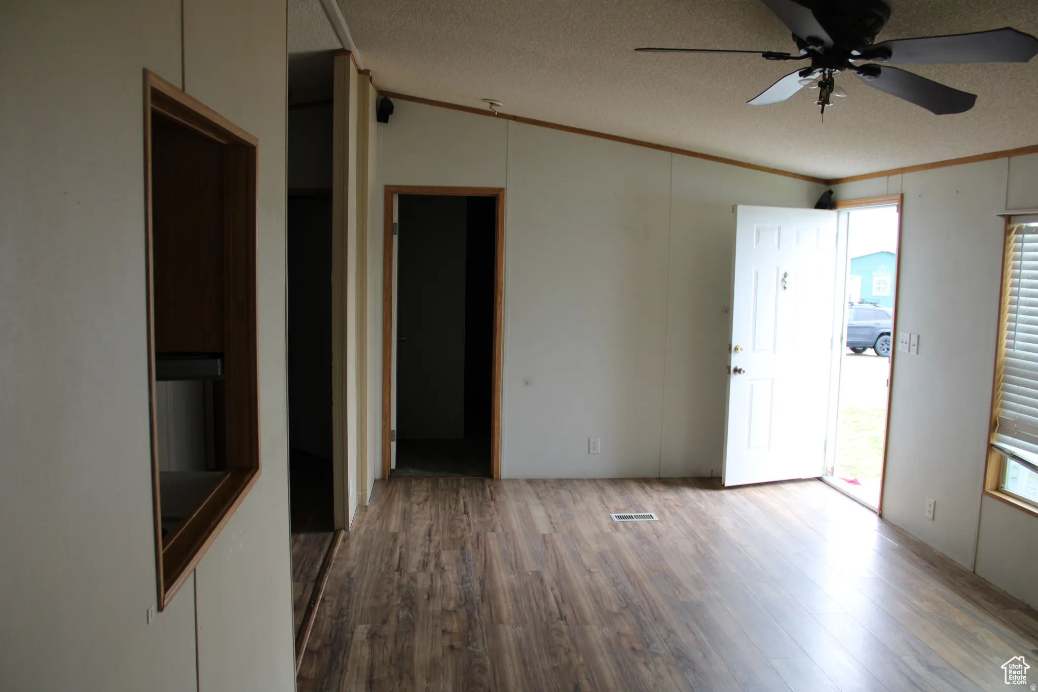 Open living space featuring wood-finish flooring, a ceiling fan, and a front entry door with a window
