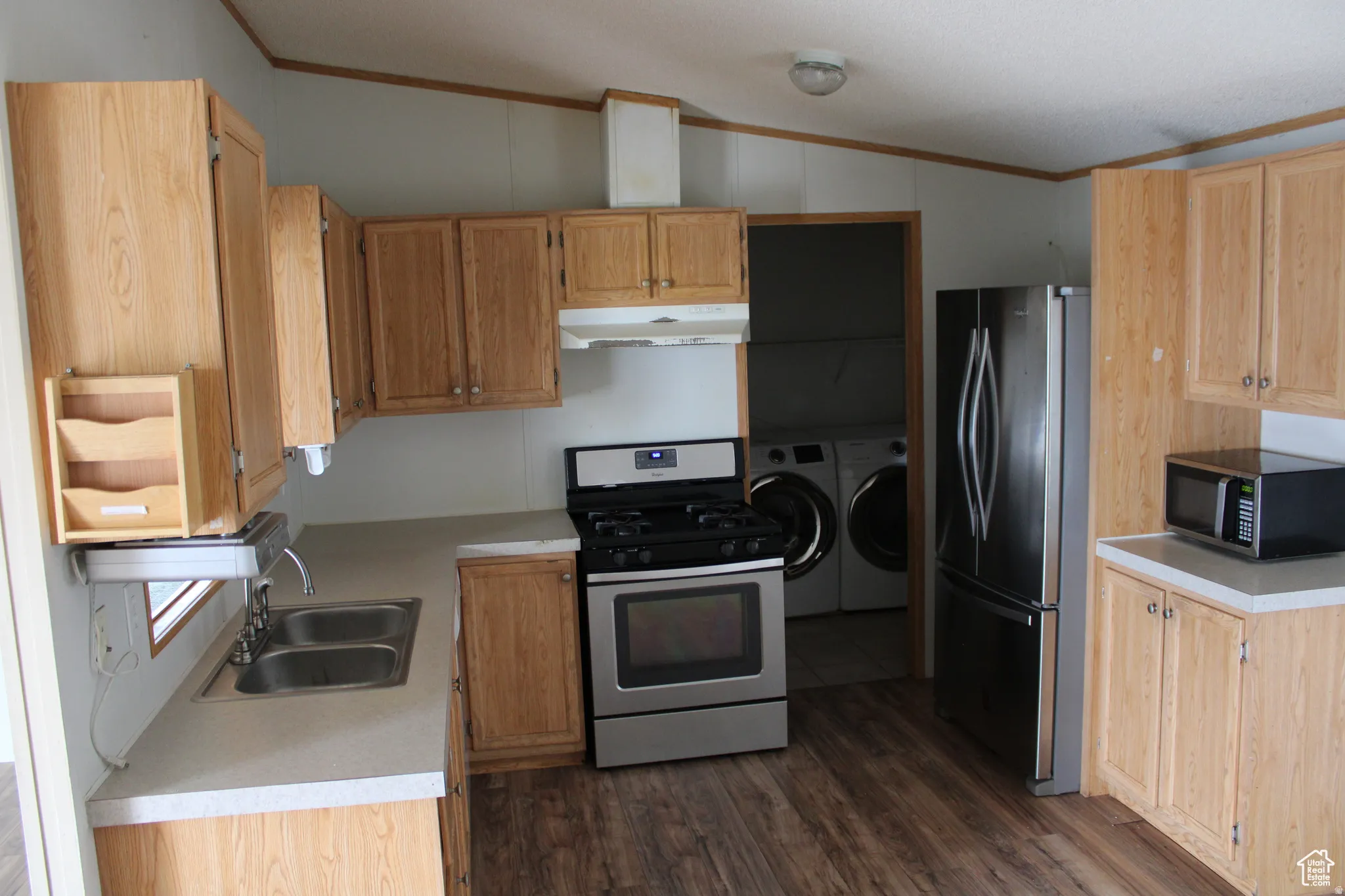 Kitchen featuring wood-finish cabinetry, stainless steel appliances, a double basin sink, and wood-finish flooring