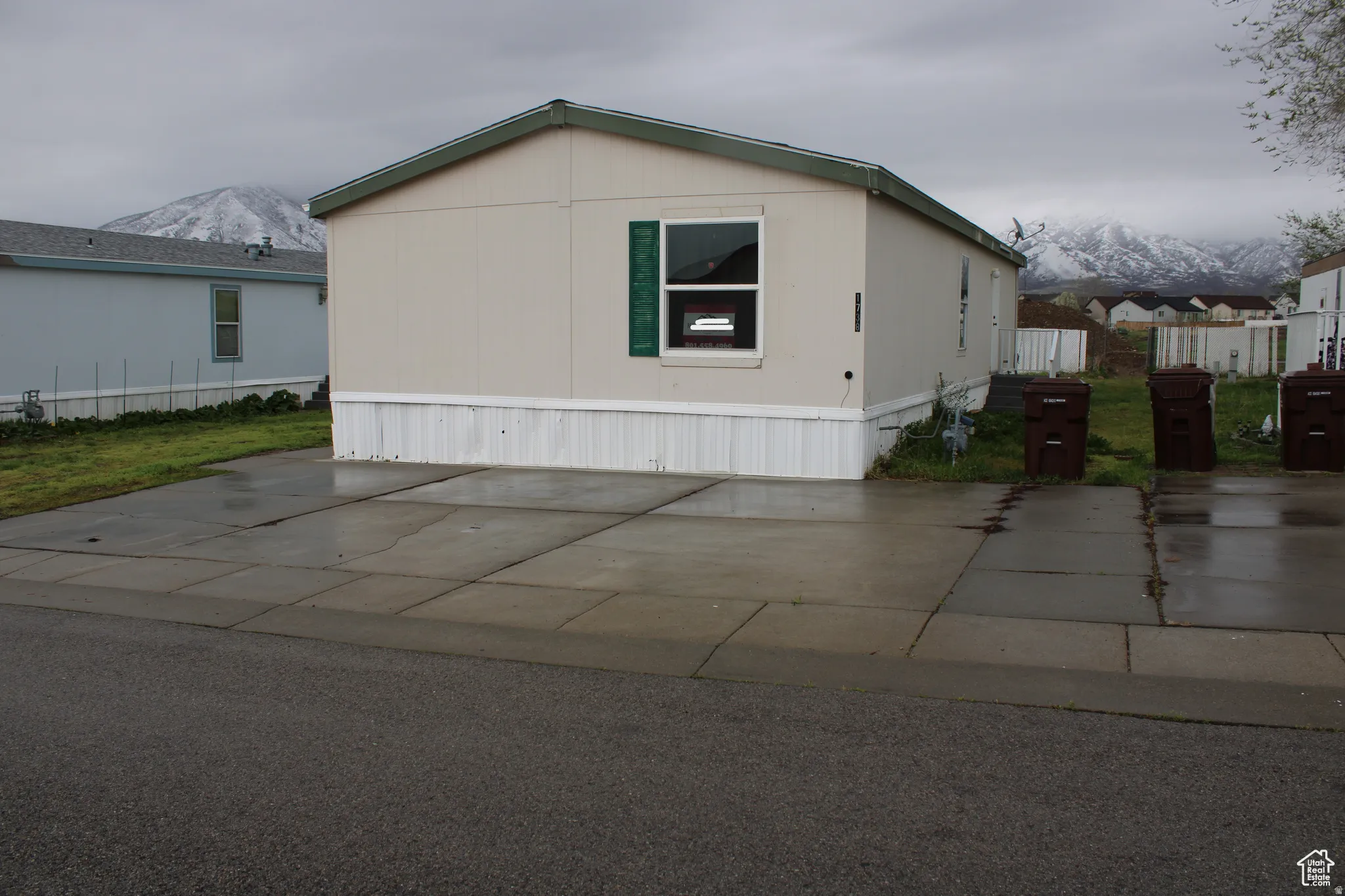 Beige exterior with green trim, featuring a concrete driveway