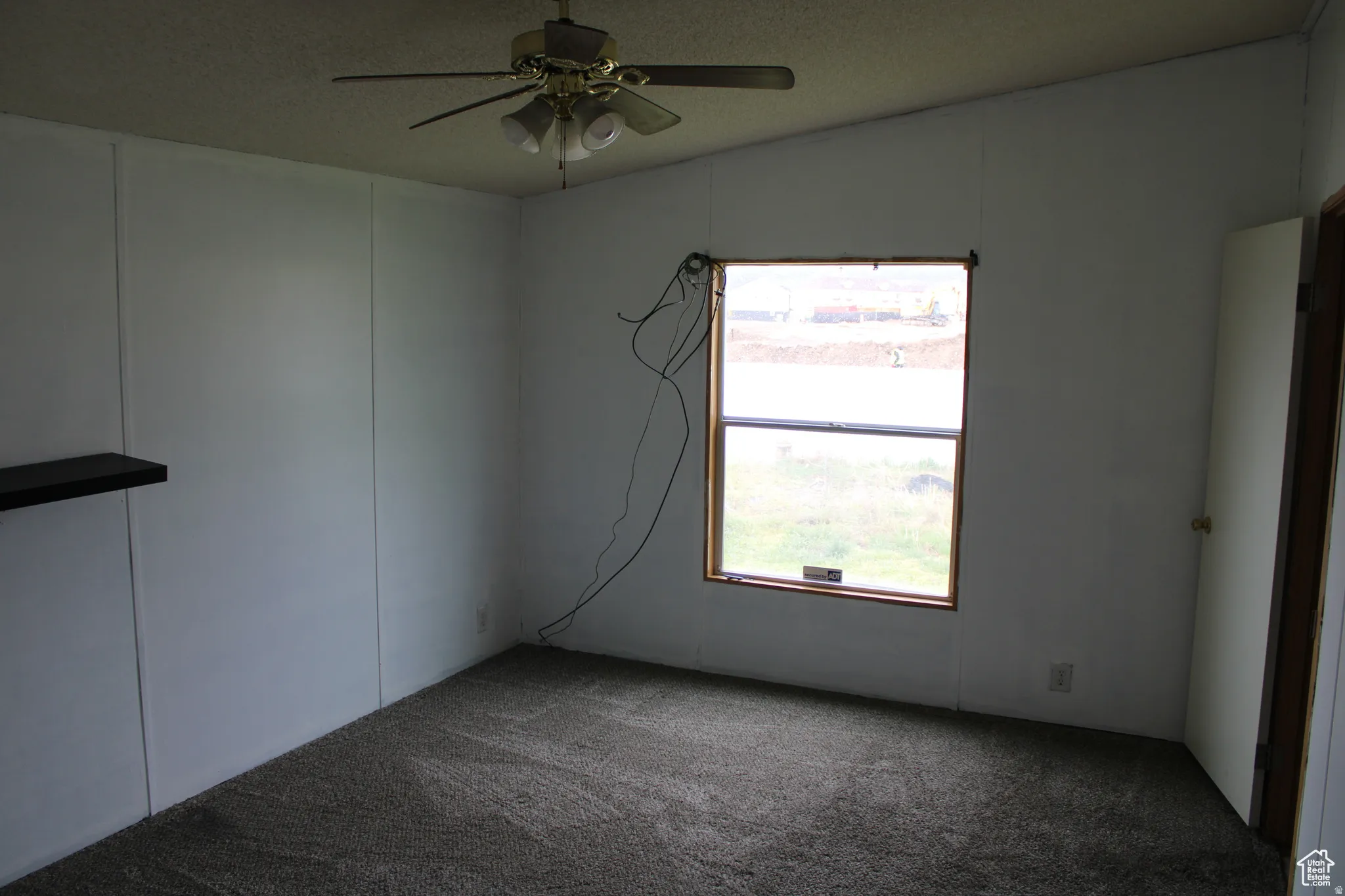 Room featuring wall-to-wall carpeting, white paneling, and a single window with wood-finish trim