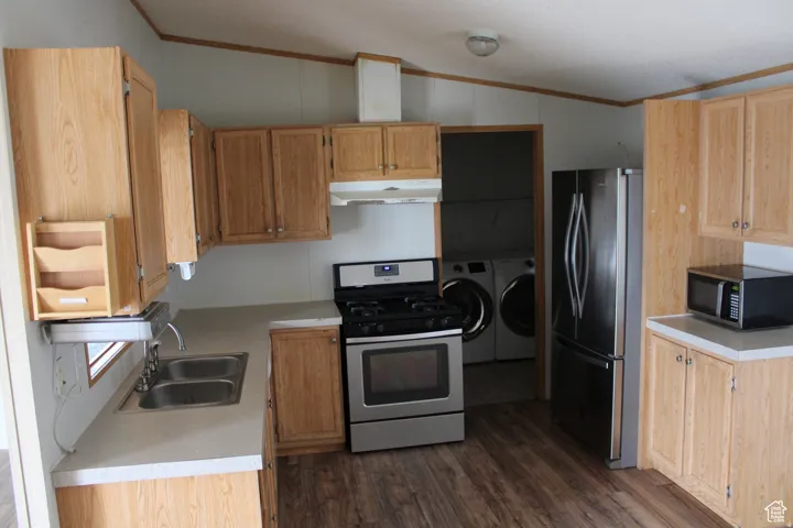 Kitchen featuring wood-finish cabinetry, stainless steel appliances, a double basin sink, and wood-finish flooring