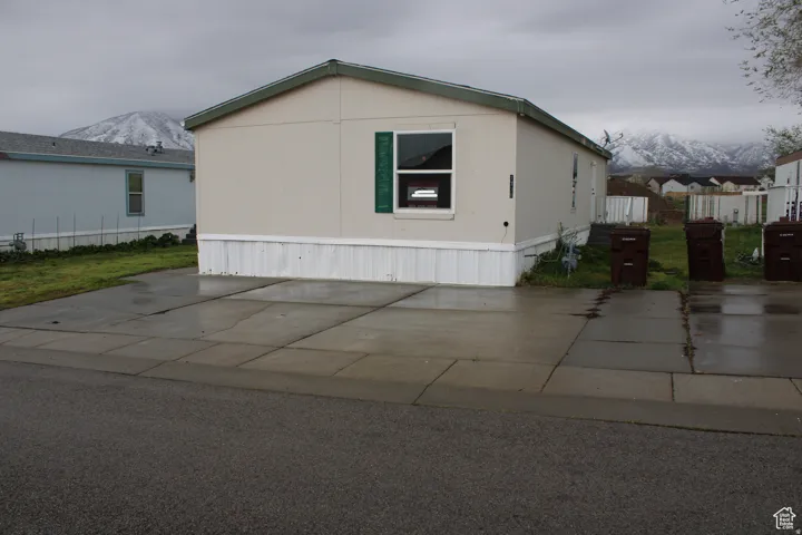 Beige exterior with green trim, featuring a concrete driveway