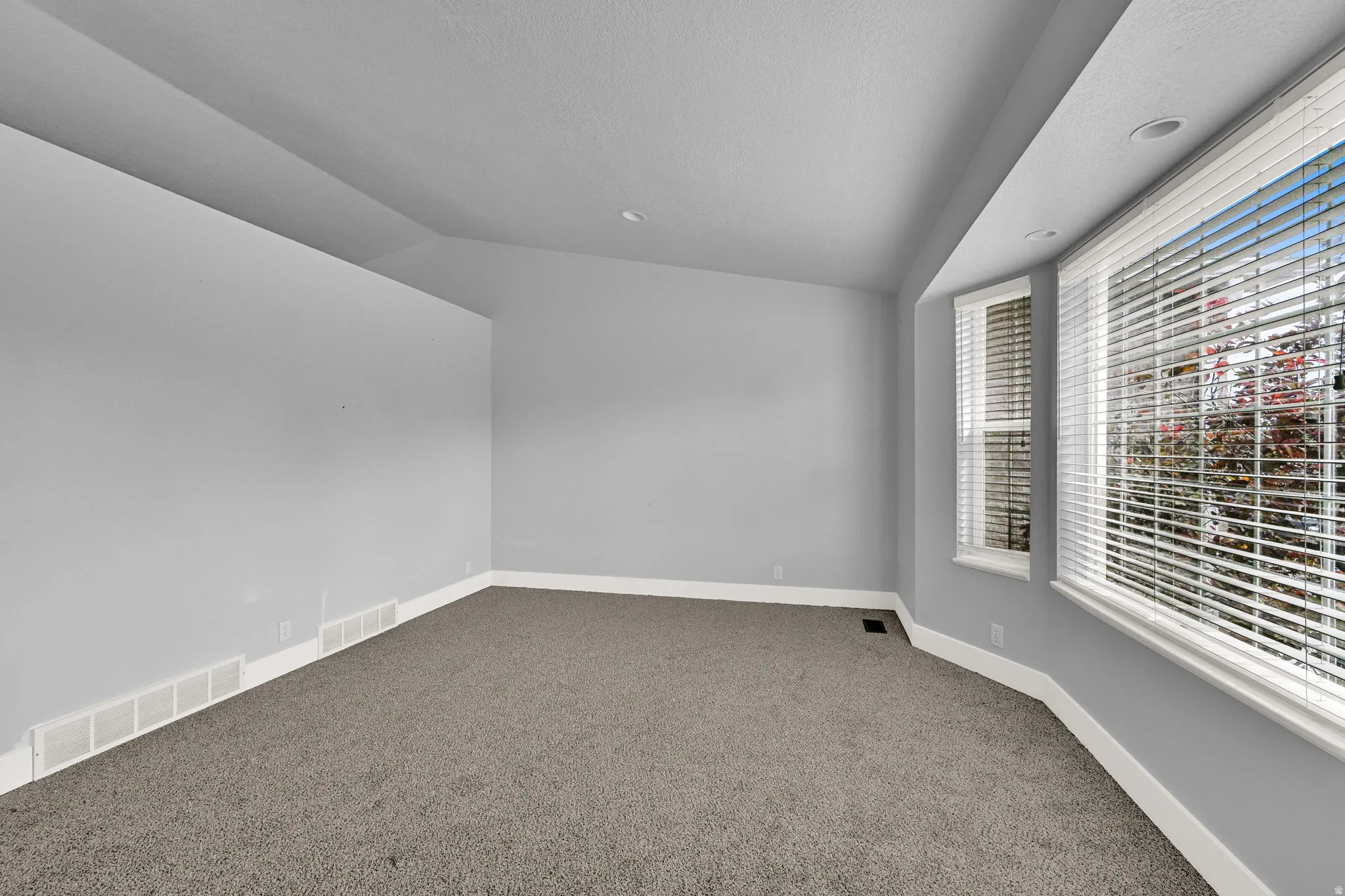 Room featuring a bay window, recessed lighting, and grey carpeting