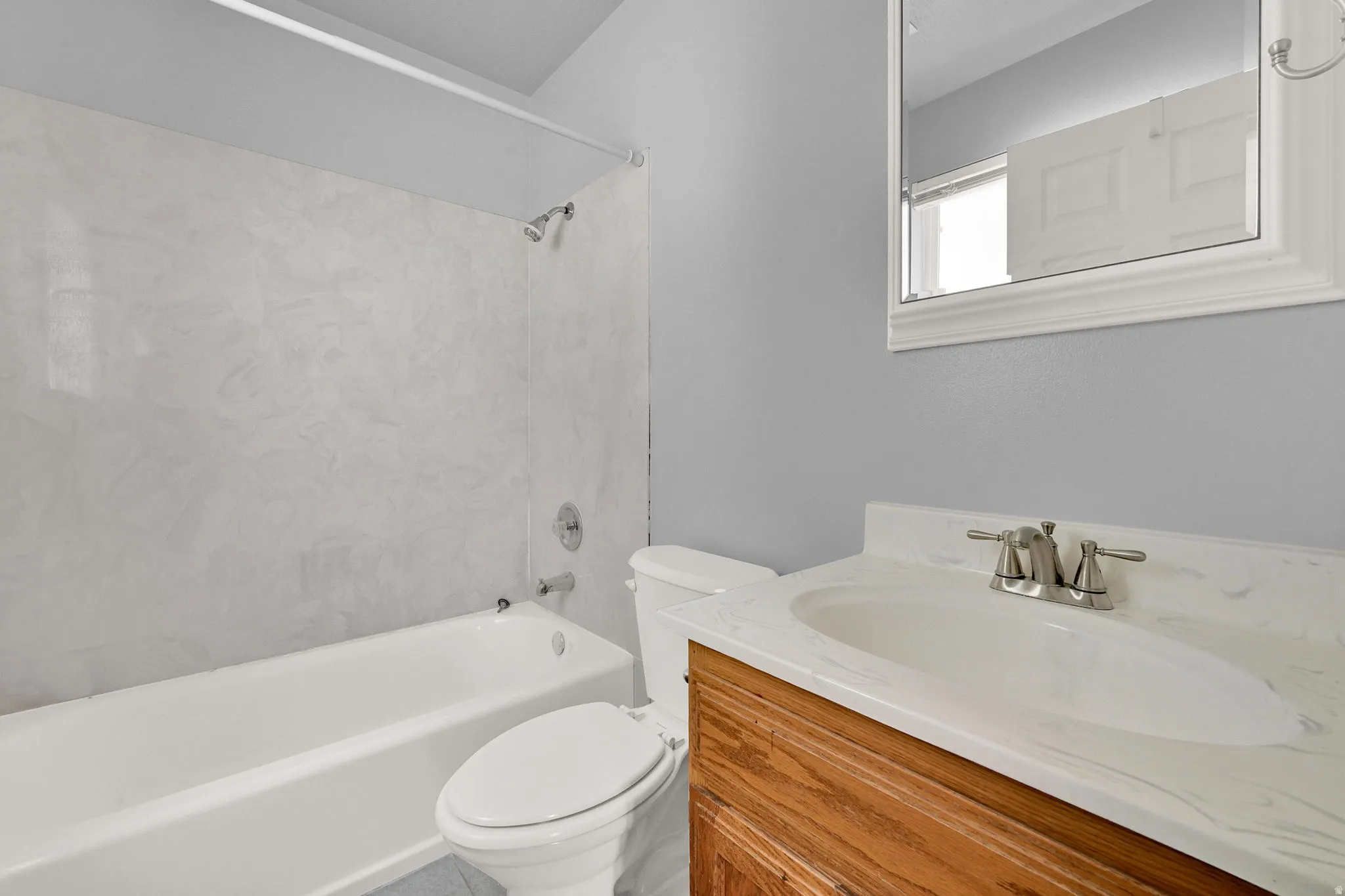 Bathroom featuring a single vanity with wood-finish cabinetry, a white countertop with integrated sink, and a brushed nickel faucet