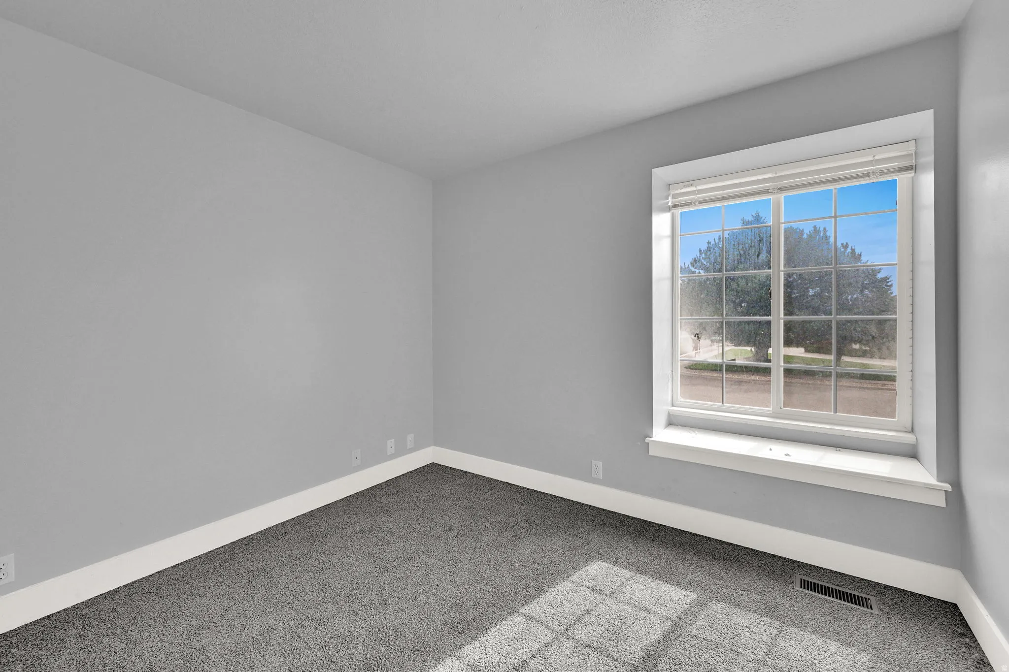 Spacious interior room featuring light gray walls and dark gray carpet