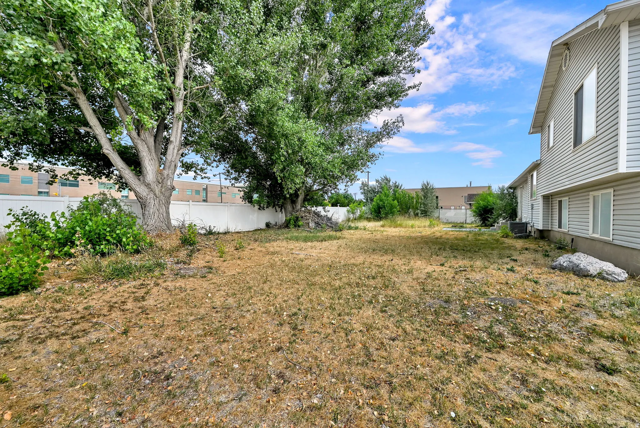 Expansive rear yard featuring mature trees and a perimeter fence
