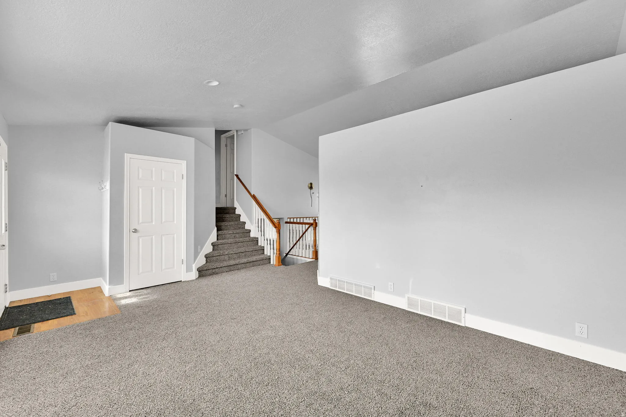 Spacious room featuring light gray walls, recessed lighting, and gray carpeting