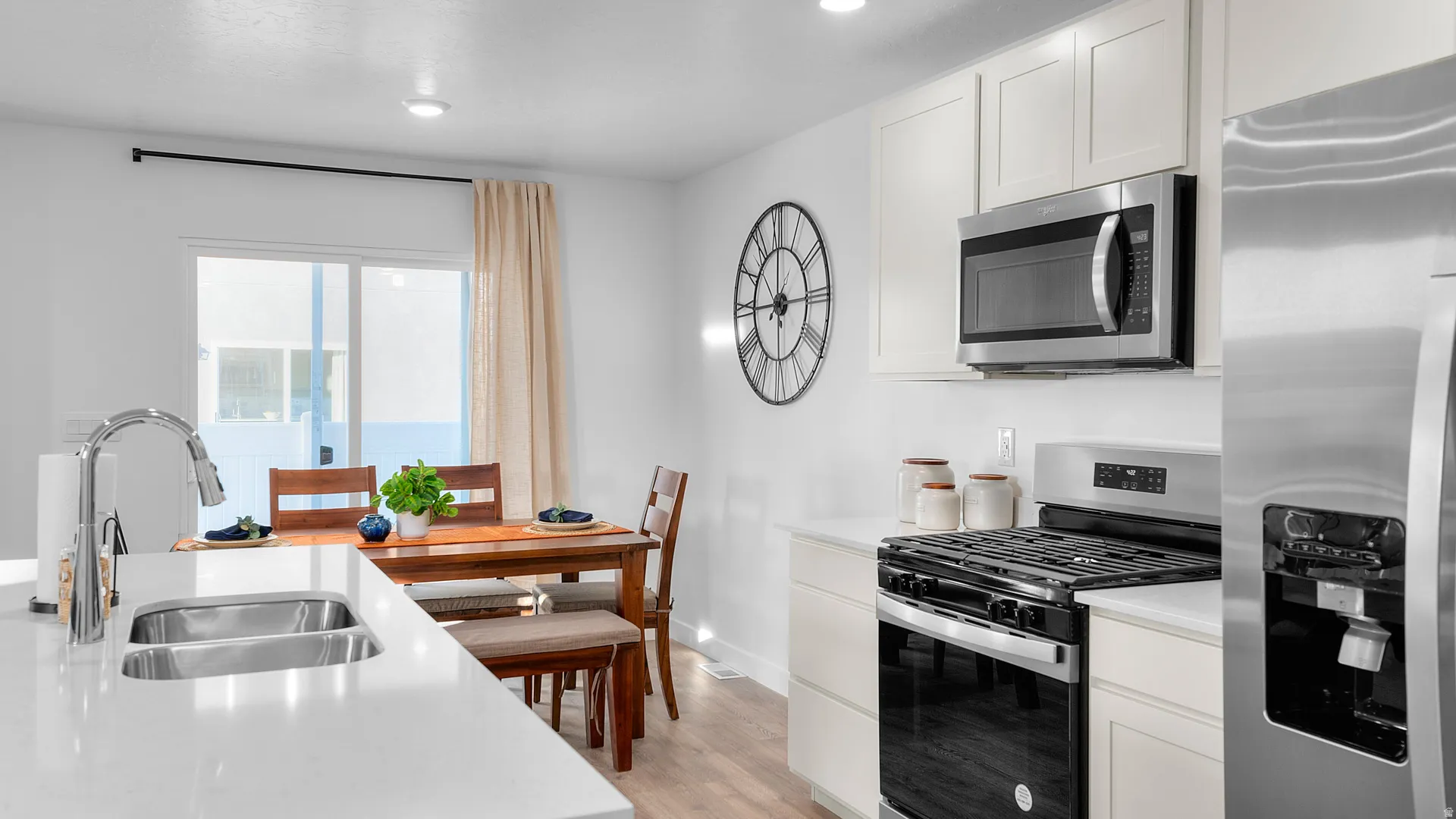 Modern kitchen featuring white cabinetry, stainless steel appliances, a double basin sink, and white countertops