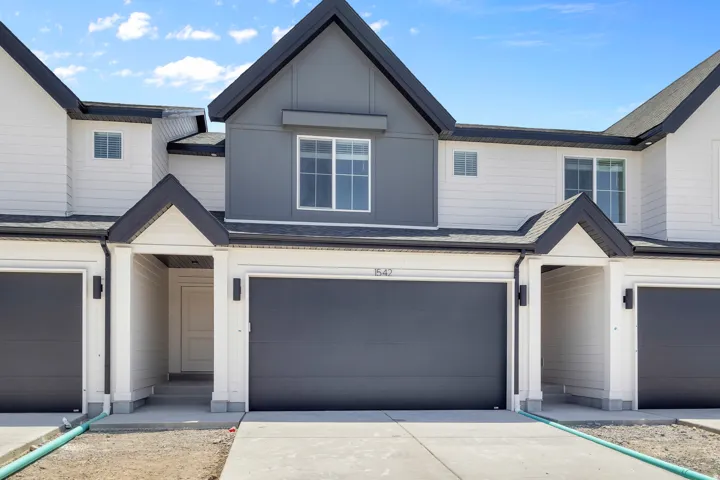 Modern townhome exterior featuring a contrasting dark gray and white color palette, a prominent front gable, and a two-car garage with a dark gray door