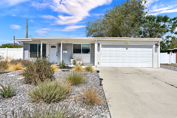 Ranch-style exterior featuring a white paneled garage door and a covered front entry