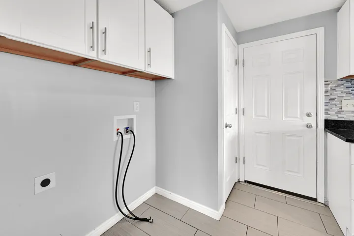 Utility area featuring white upper cabinetry with brushed nickel hardware, a laundry hookup, and wood-finish tile flooring