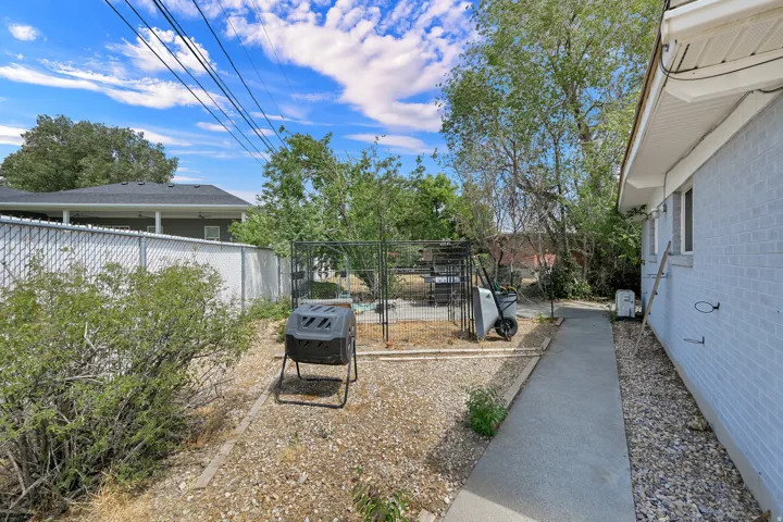 Side yard featuring a concrete walkway, gravel landscaping, and a chain-link fence