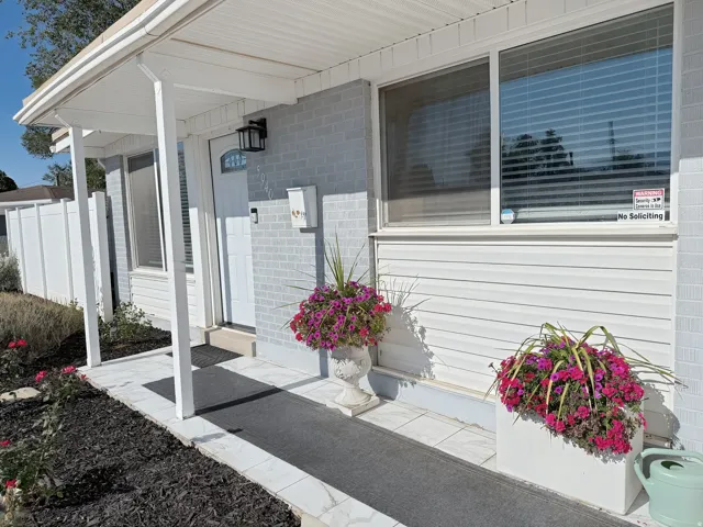 Covered entry with white vinyl siding and light grey painted brick facade