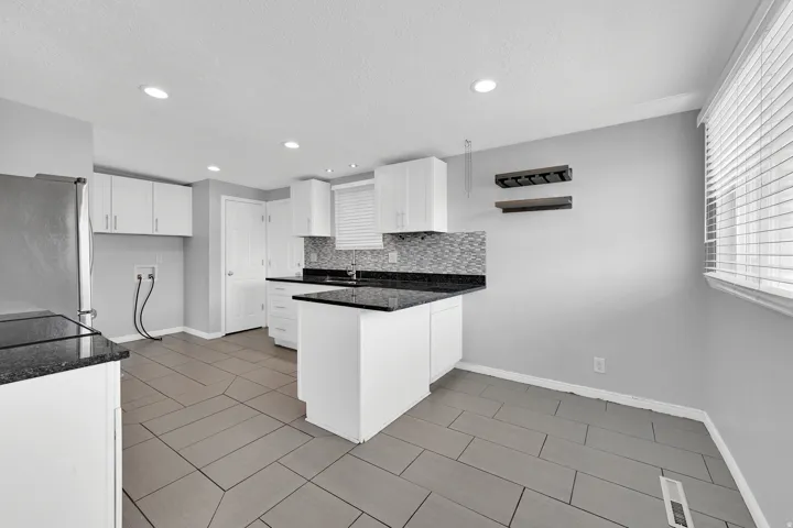 Kitchen featuring white cabinetry, dark countertops, a tile backsplash, and recessed lighting