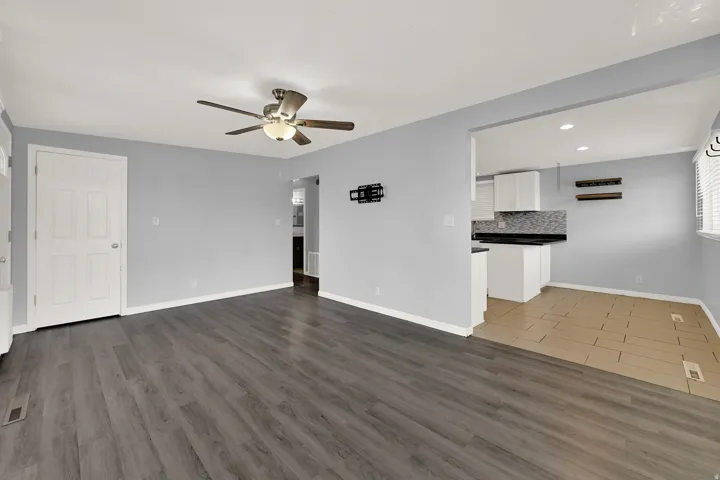 Spacious interior featuring wood-finish flooring, a contemporary ceiling fan with integrated lighting, and a white six-panel door