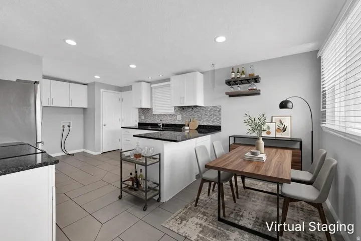 Kitchen area featuring white cabinetry, dark countertops, and a mosaic tile backsplash