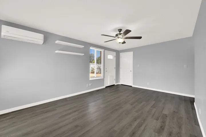Spacious room featuring wood-finish flooring, light grey walls, and white trim