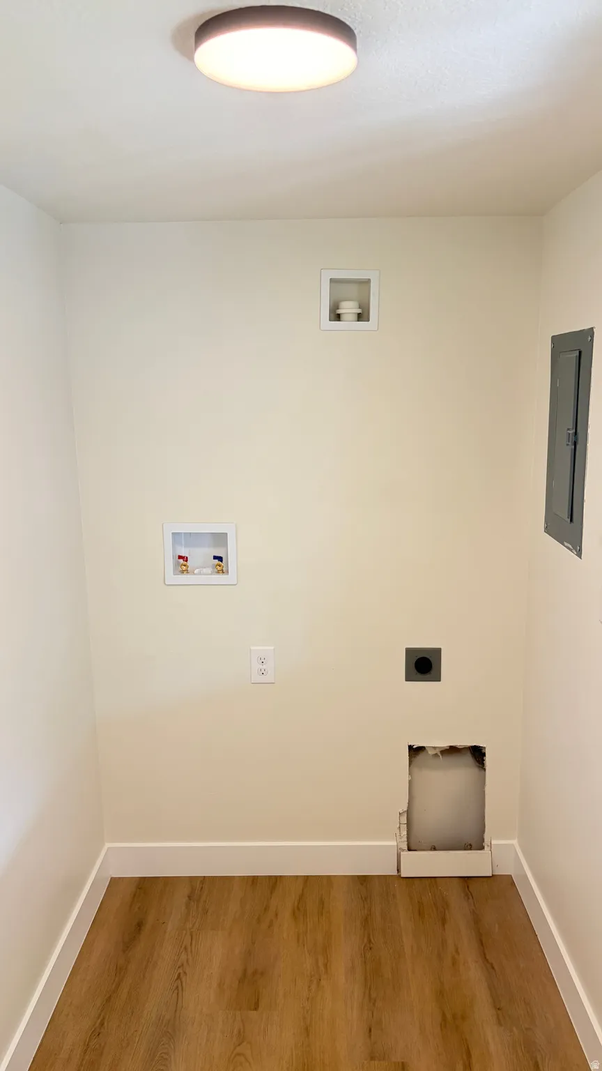 Dedicated laundry area featuring wood-finish flooring, white baseboards, and a flush-mount ceiling light