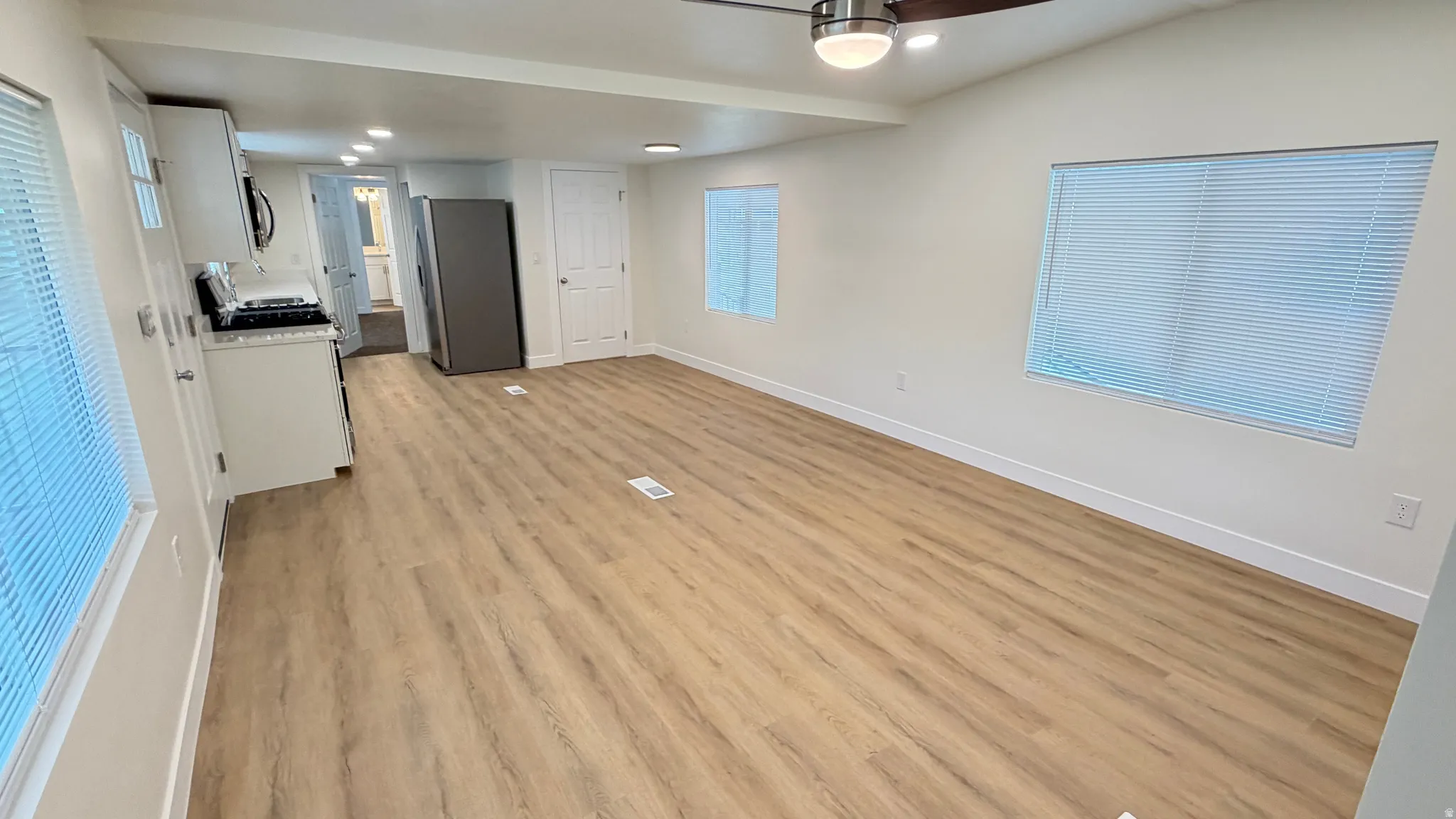 Open-concept living space featuring wood-finish flooring, white baseboards, and neutral wall paint