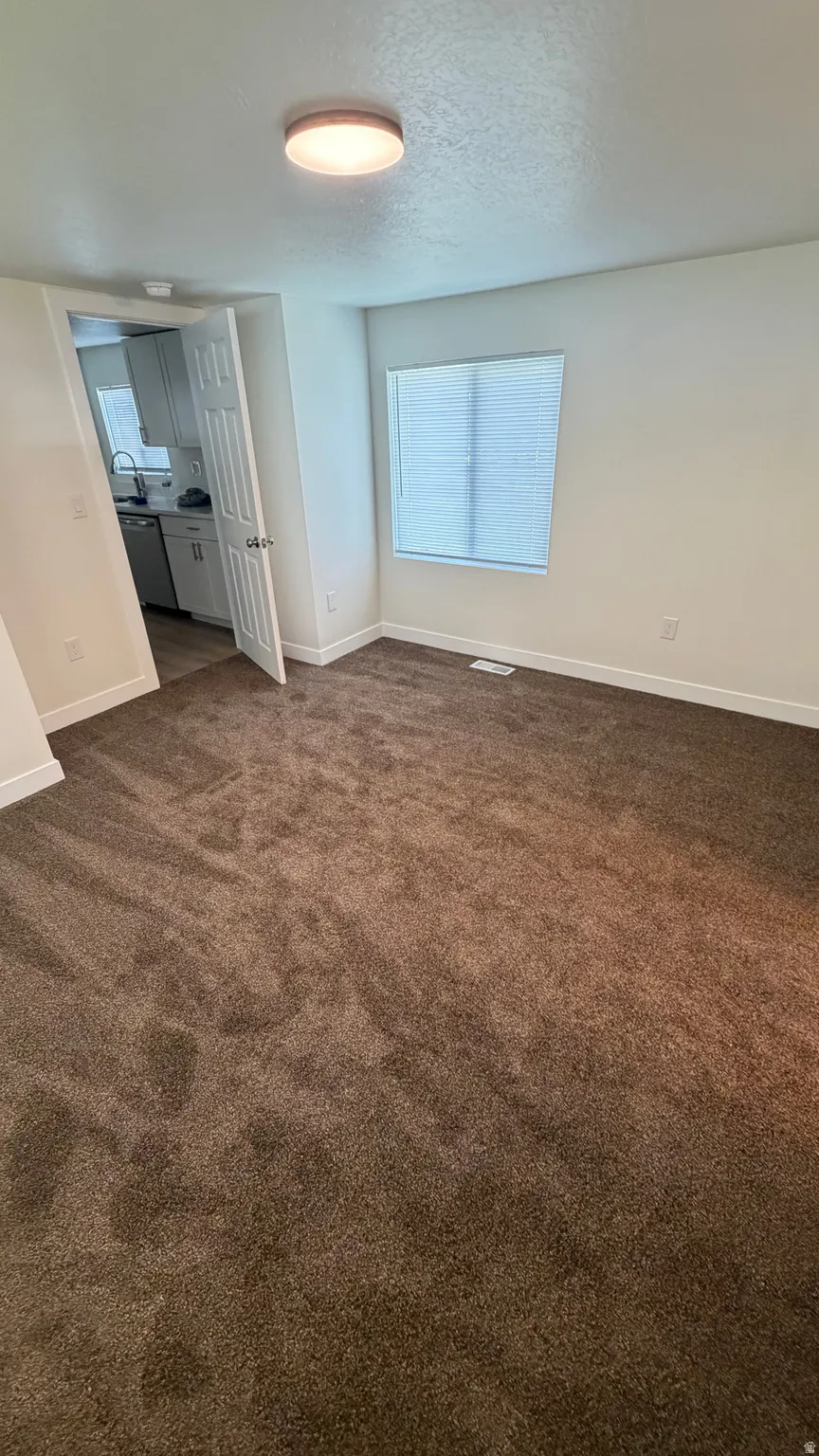 Spacious room featuring neutral carpeting and a window with blinds