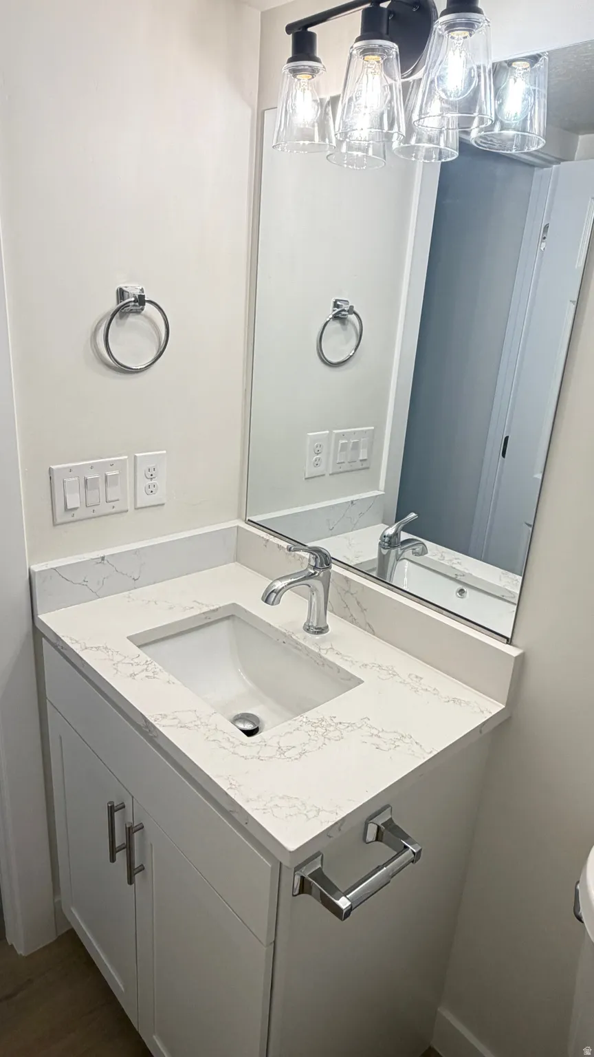 Contemporary vanity featuring a white cabinet, integrated sink, and a stone-finish countertop