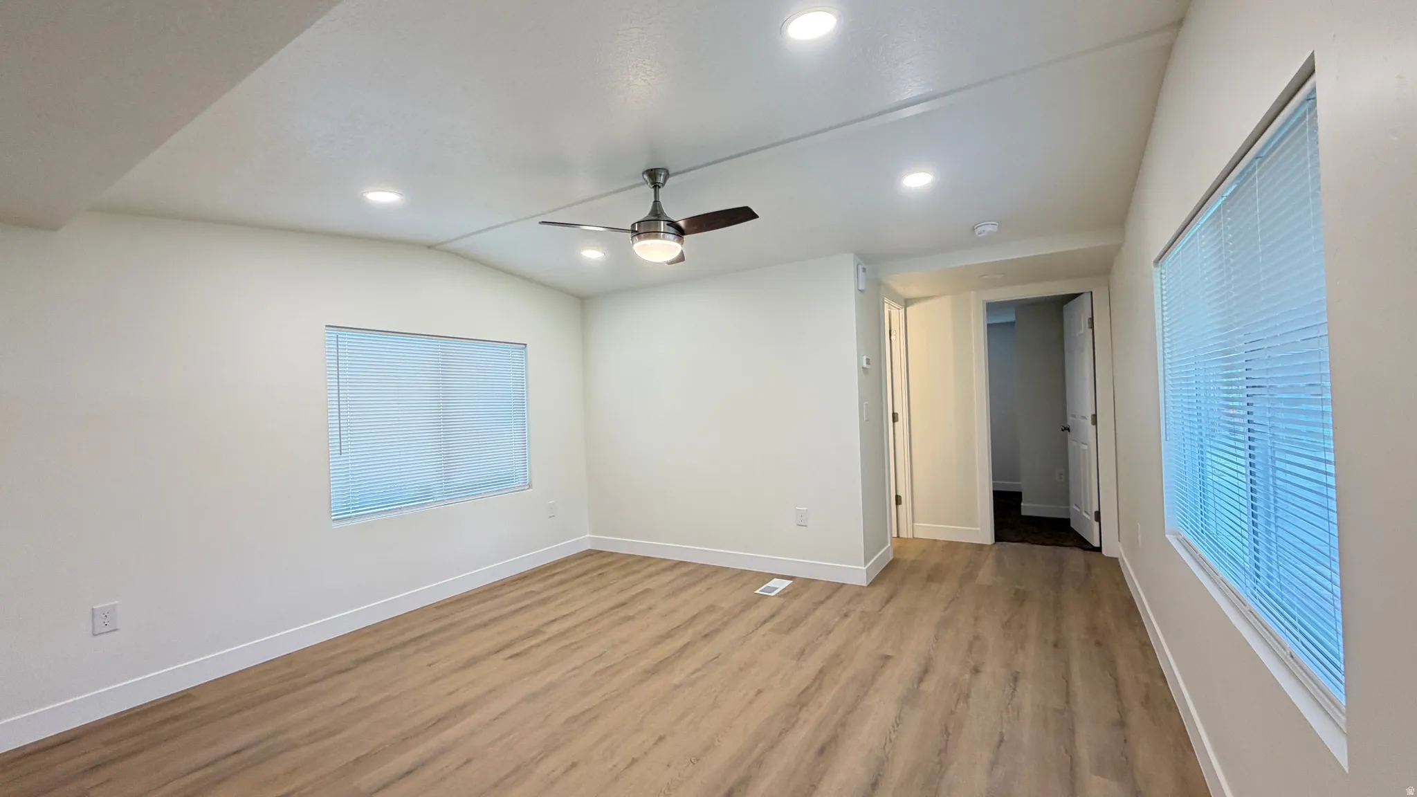 Spacious room featuring wood-finish flooring, recessed lighting, and a ceiling fan