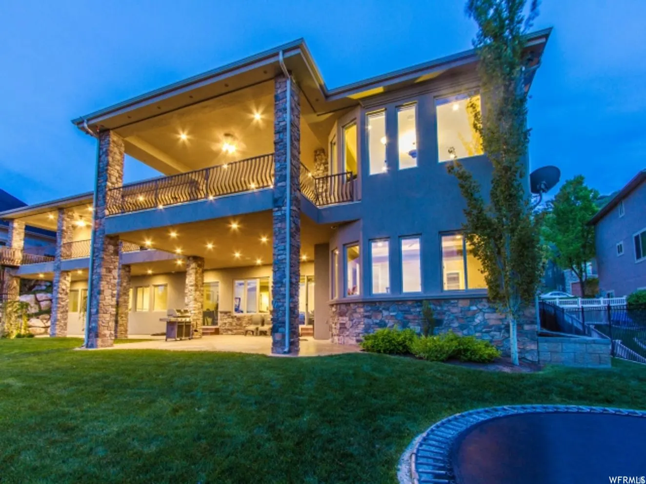 Two-story exterior featuring stone columns and a stucco facade