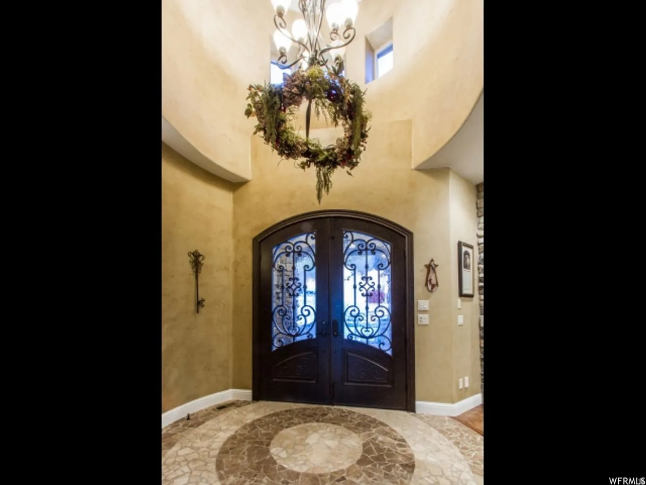 Arched double entry doors featuring decorative wrought iron and glass panels