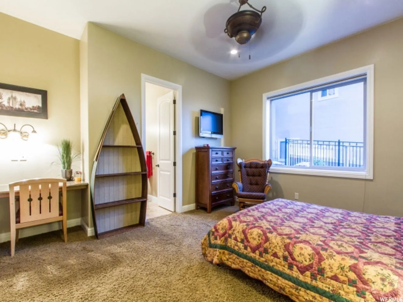 Warm neutral wall tones featuring a textured carpet flooring and a ceiling fan with integrated lighting