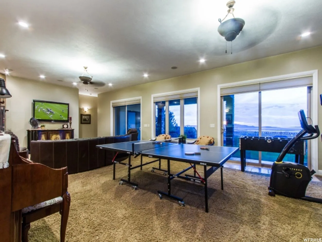 Spacious recreation room featuring multiple sliding glass doors, recessed lighting, and ceiling fans