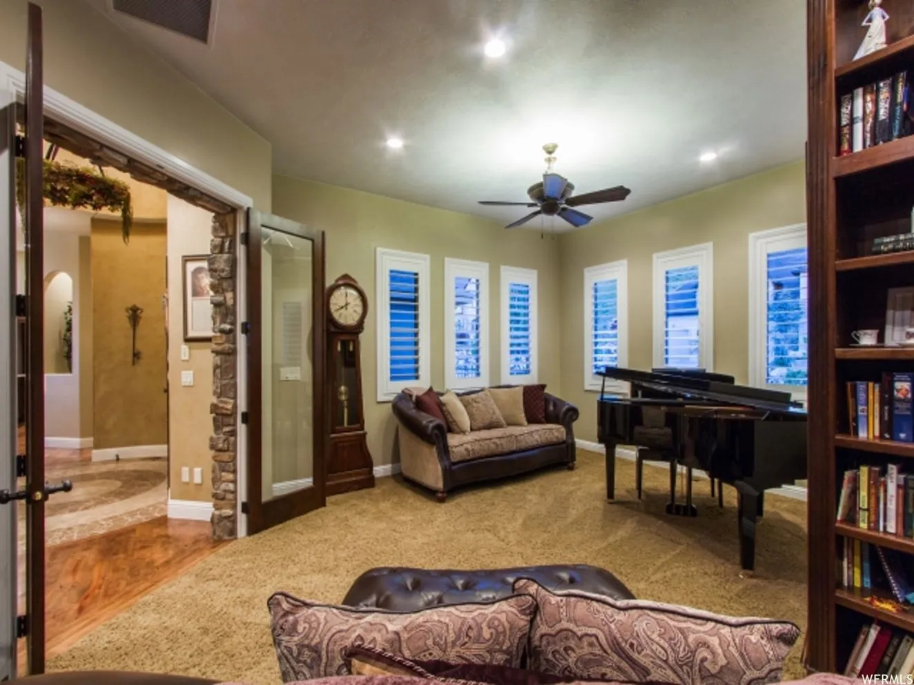 Carpeted interior space featuring multiple windows with white plantation shutters